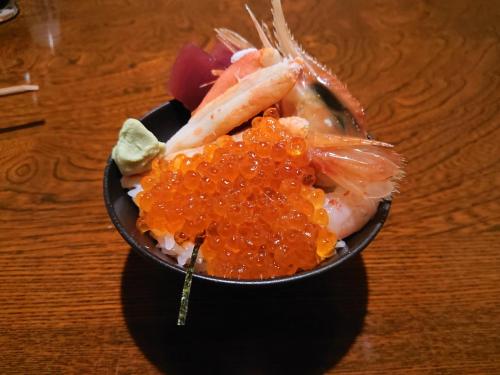 eine schwarze Schüssel mit Essen auf einem Holztisch in der Unterkunft Sea Side Stay / Vacation STAY 1785 in Abashiri