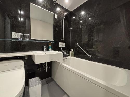 a bathroom with a tub and a sink and a bath tub at Richmond Hotel Morioka Ekimae in Morioka