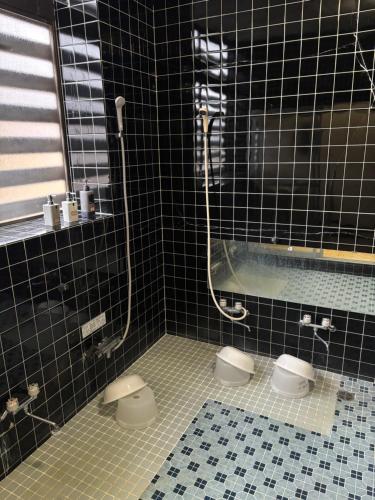 a black tiled bathroom with two toilets and a tub at ロッヂ 雪ん子 in Yuzawa