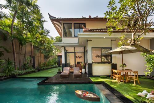 a house with a swimming pool in front of a house at Red Lotus Seminyak Villa in Seminyak