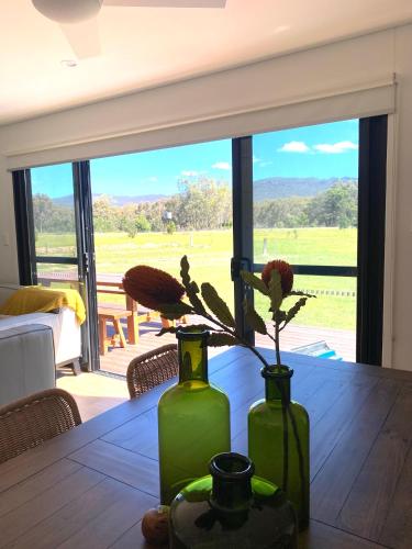 two green vases with flowers on a wooden table at Grampians View Eco Retreat in Halls Gap