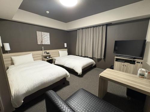 a hotel room with two beds and a flat screen tv at Hotel Route-Inn Shinfujieki Minami in Fuji