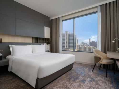 a hotel room with a large white bed and a desk at Mercure Bangkok Siam in Bangkok