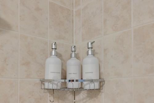 three bottles of soap on a shelf in a bathroom at Luxe 3-Bedroom Lakeview Condo, Free parking ,Walk to CN Tower, Scotiabank Arena & Rogers Centre in Toronto