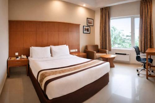 ein Hotelzimmer mit einem großen Bett und einem Schreibtisch in der Unterkunft La Franklin Hotel in Bhubaneshwar