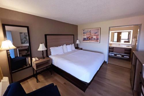 een hotelkamer met een groot bed en een spiegel bij Baymont by Wyndham Culpeper in Culpeper