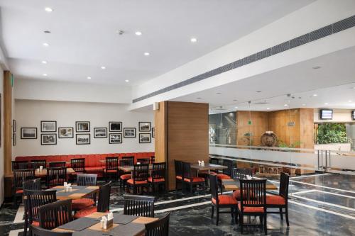 ein Restaurant mit Holztischen und roten Stühlen in der Unterkunft La Franklin Hotel in Bhubaneshwar