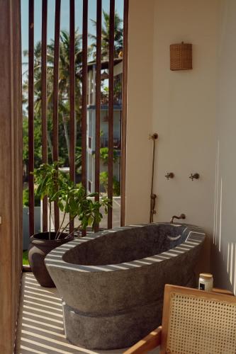 a large stone tub sitting on a porch with a plant at Soul Temple Boutique Hotel ADULTS ONLY in Ahangama