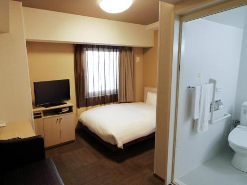 ein Hotelzimmer mit Bett und Fernseher in der Unterkunft Hotel Route-Inn Shimizu Inter in Shizuoka