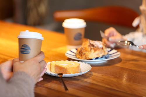 Zwei Personen halten Kaffeetassen auf einem Tisch mit Essen. in der Unterkunft Umikara in Unzen