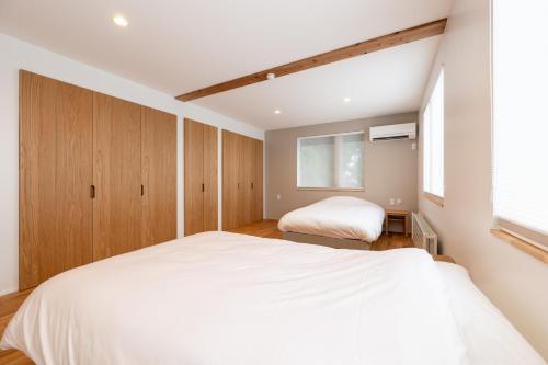 a bedroom with a large white bed and a window at Bella Vista Ski Lodge in Nozawa Onsen