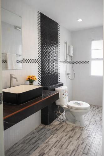 a bathroom with a tub and a toilet and a sink at Grand Chalong Family House in Chalong