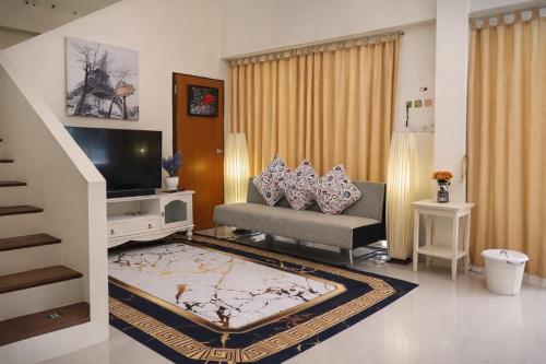 a living room with a couch and a television at Grand Chalong Family House in Chalong