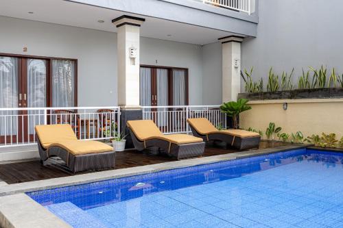 a hotel swimming pool with chairs and a swimming pool at Cove Puspa Canggu in Canggu