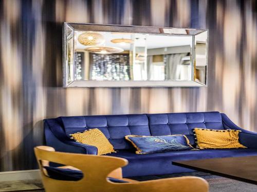 un canapé bleu dans un salon avec un miroir dans l'établissement Mercure Milton Keynes Hotel, à Milton Keynes
