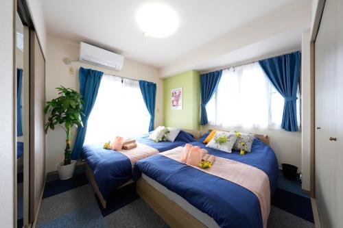 two beds in a room with blue curtains at AO301 - Tokyo Stay Spacious Apartment Direct Train to Narita & Asakusa in Tokyo