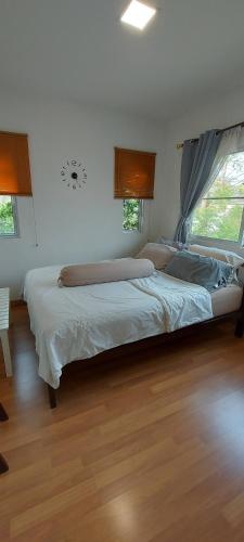 a large bed in a bedroom with wood floors at Cosy Preuksa House 120 in Bang Yai