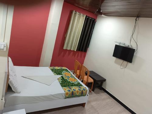 ein Schlafzimmer mit einem Bett und einem Tisch und einem Fernseher in der Unterkunft sai villa lodging and boarding in Virār