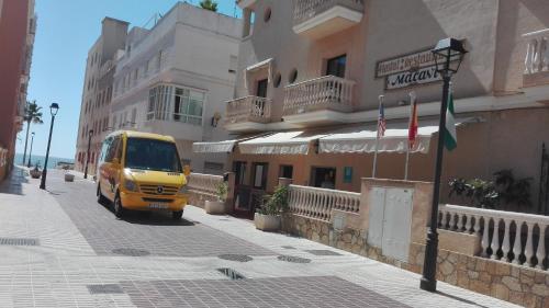 Una furgoneta amarilla conduciendo por una calle al lado de un edificio en Macavi, en Rota