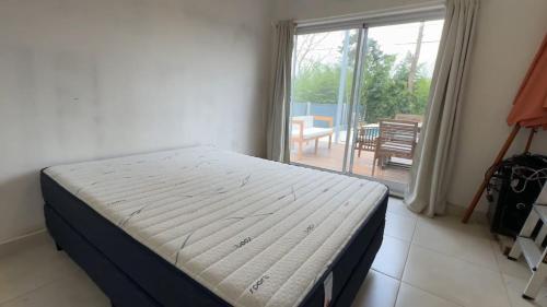 een bed in een slaapkamer met uitzicht op een patio bij Homero duplex in Villa Gesell
