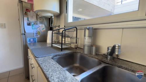 een aanrecht met een wastafel en een raam bij Homero duplex in Villa Gesell