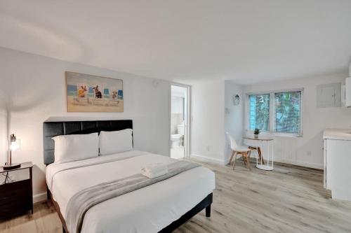 a white bedroom with a large bed and a table at Tropical Oasis Studio w Pool in Fort Lauderdale