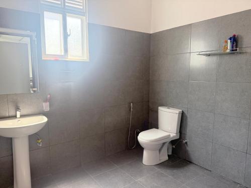 a bathroom with a white toilet and a sink at Sunray Homes in Disagewatta