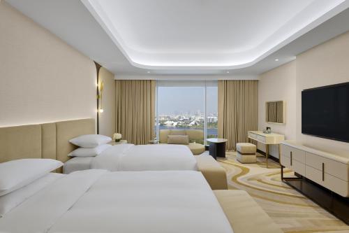 a hotel room with two beds and a flat screen tv at Grand Hyatt Dubai Resort & Waterpark in Dubai