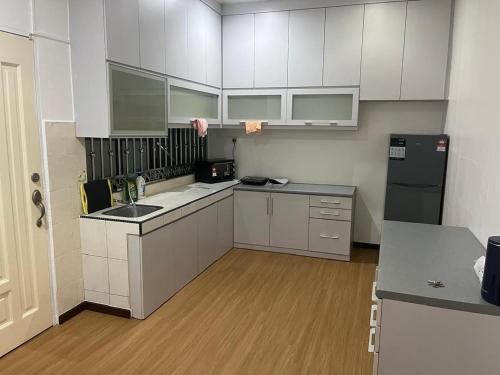 een keuken met witte kasten en een zwarte koelkast bij LIY Homestay in Gua Sai