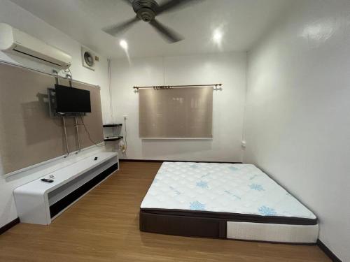 een kamer met een bed en een flatscreen-tv bij LIY Homestay in Gua Sai