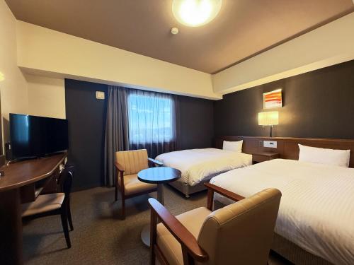 a hotel room with two beds and a desk at Hotel Route-Inn Ichinoseki Inter in Ichinoseki