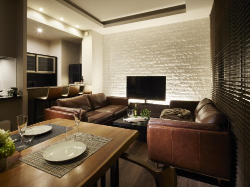 een woonkamer met leren banken en een tafel bij Minn Chitose in Chitose