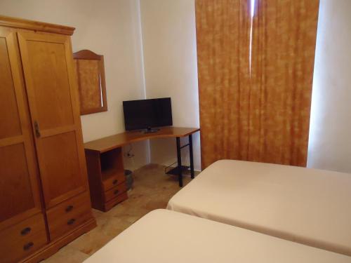 a bedroom with a bed and a desk with a television at Hotel Antequera Rural Fortes La Nuit in Mollina