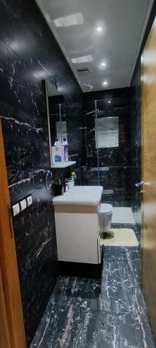 a black bathroom with a sink and a toilet at Temara wifak in Temara