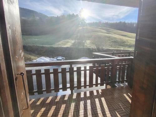 een deur naar een balkon met uitzicht op een veld bij Appartement type chalet savoyard cosy in Aillon-le-Jeune