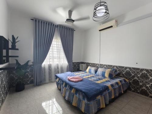 a bedroom with a bed with a blue comforter and a window at Cocasa Homestay 1 in Kuala Terengganu