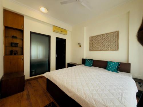 a bedroom with a white bed with blue pillows at Minimalist Escape in Gurgaon