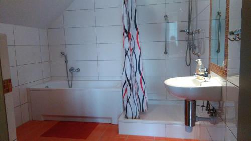 a bathroom with a tub and a sink and a shower curtain at Noclegi Przylesie in Rychnowy
