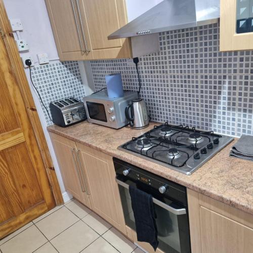 a kitchen with a stove and a microwave at 4 Norman House Leicester in Leicester