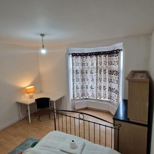 a bedroom with a bed and a window with a desk at 4 Norman House Leicester in Leicester