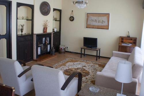 a living room with a couch and chairs and a tv at Burgo's House in Porto