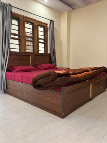 a bedroom with a large wooden bed with red sheets at Hathayogashram Hostel in Rishīkesh