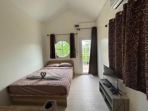 a bedroom with a bed and a tv and a window at RT House Resort in Ban Phawon