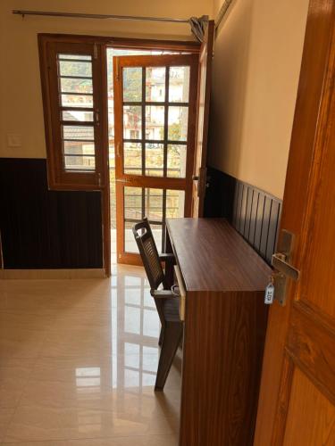 een kamer met een bureau met een stoel en een raam bij Hathayogashram Hostel in Rishīkesh