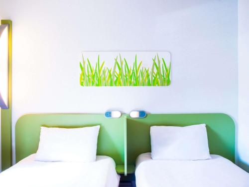 une chambre avec deux lits et un tableau d'herbe au mur dans l'établissement ibis budget Issoire, à Issoire