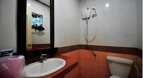 une salle de bains avec lavabo, toilettes et miroir dans l'établissement Phuttachot Resort, sur les Îles Phi Phi
