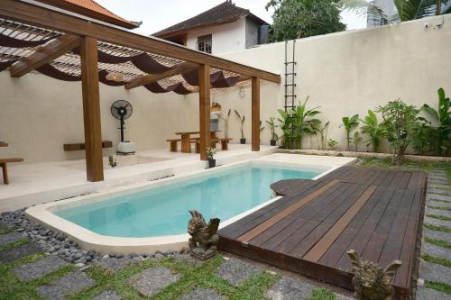 una piscina con terrazza in legno accanto a una casa di Avaya Boutique Hostel by Ayodya Beach Inn a Legian