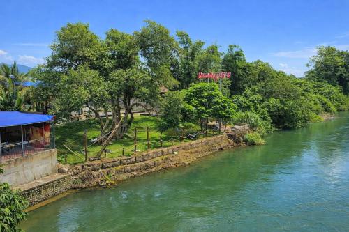 Tánh LinhHomestay 25 tháng 12 Tàpao - Đồng Kho - Tánh Linh的一条河，两岸树木葱郁，河边有一栋建筑。