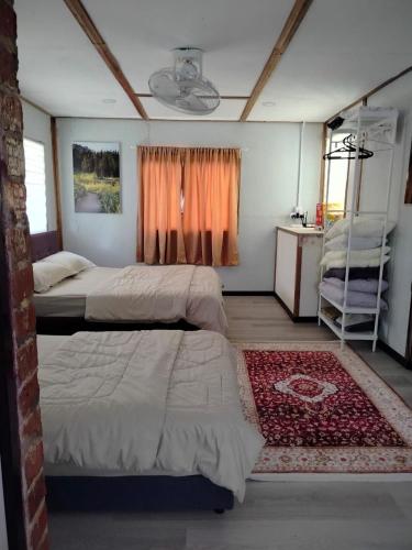 a bedroom with two beds and a red rug at Tokpa Tokma's Haven in Jertih