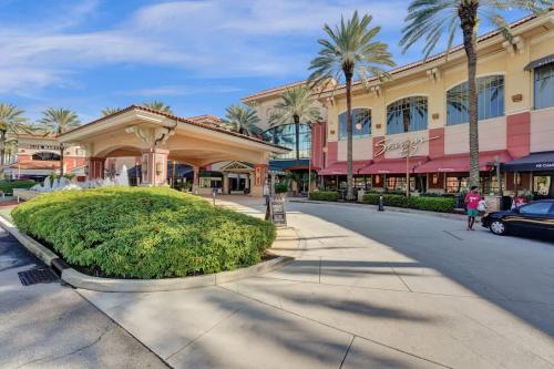 a street in front of a shopping mall with palm trees at Rustic Retreats Cozy 1BR For 4 Guests Minutes From Las Olas in Fort Lauderdale